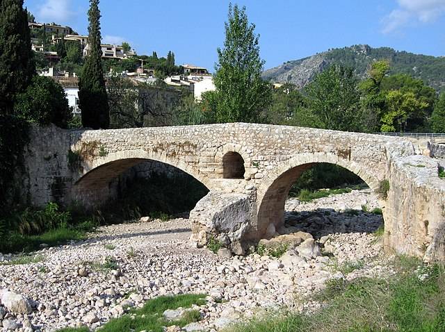 Historic stone bridge spanning a dry, rocky river bed.