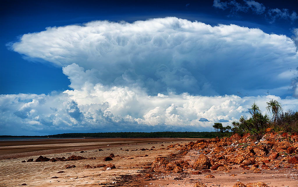 Large thunderstorm with red colored rocks in foreground.