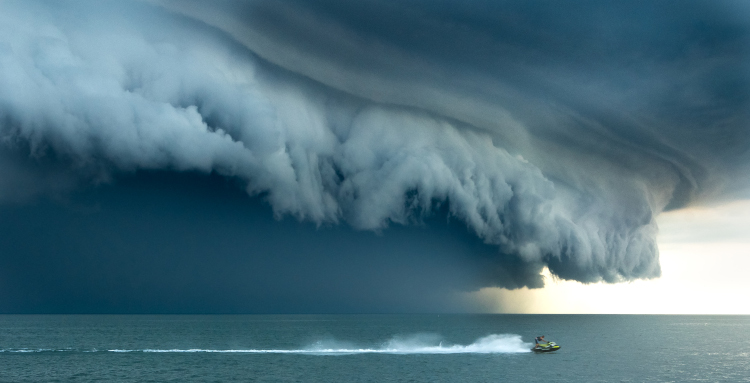 Shelf cloud over a lake with a jetski in the foreground.